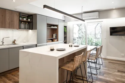 Cocina moderna escandinava con isla grande y sillas de ratán — proyecto Depto Virrey del Pino, por Ayelen Mayer Arquitectura, en Buenos Aires